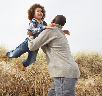 Dad lifting his laughing child in a field